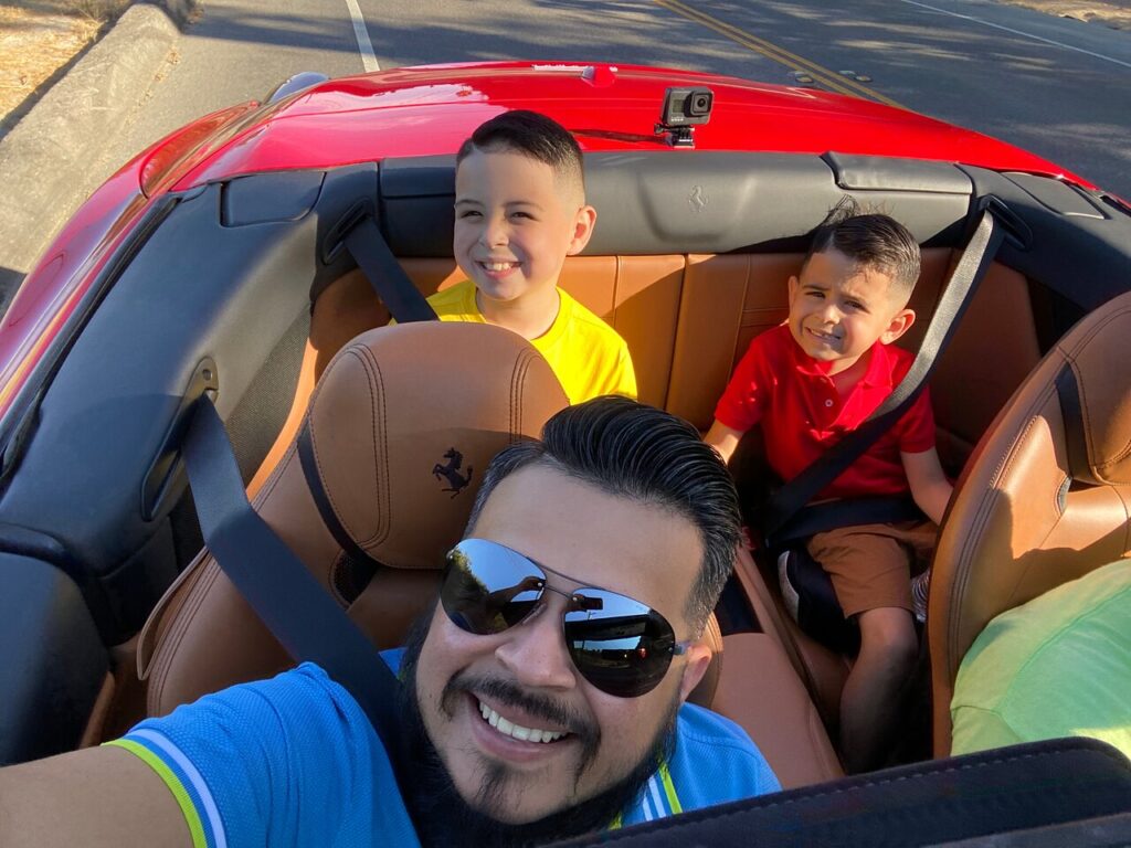 Happy family enjoying a Ferrari convertible driving experience in Hollywood with scenic city views in the background